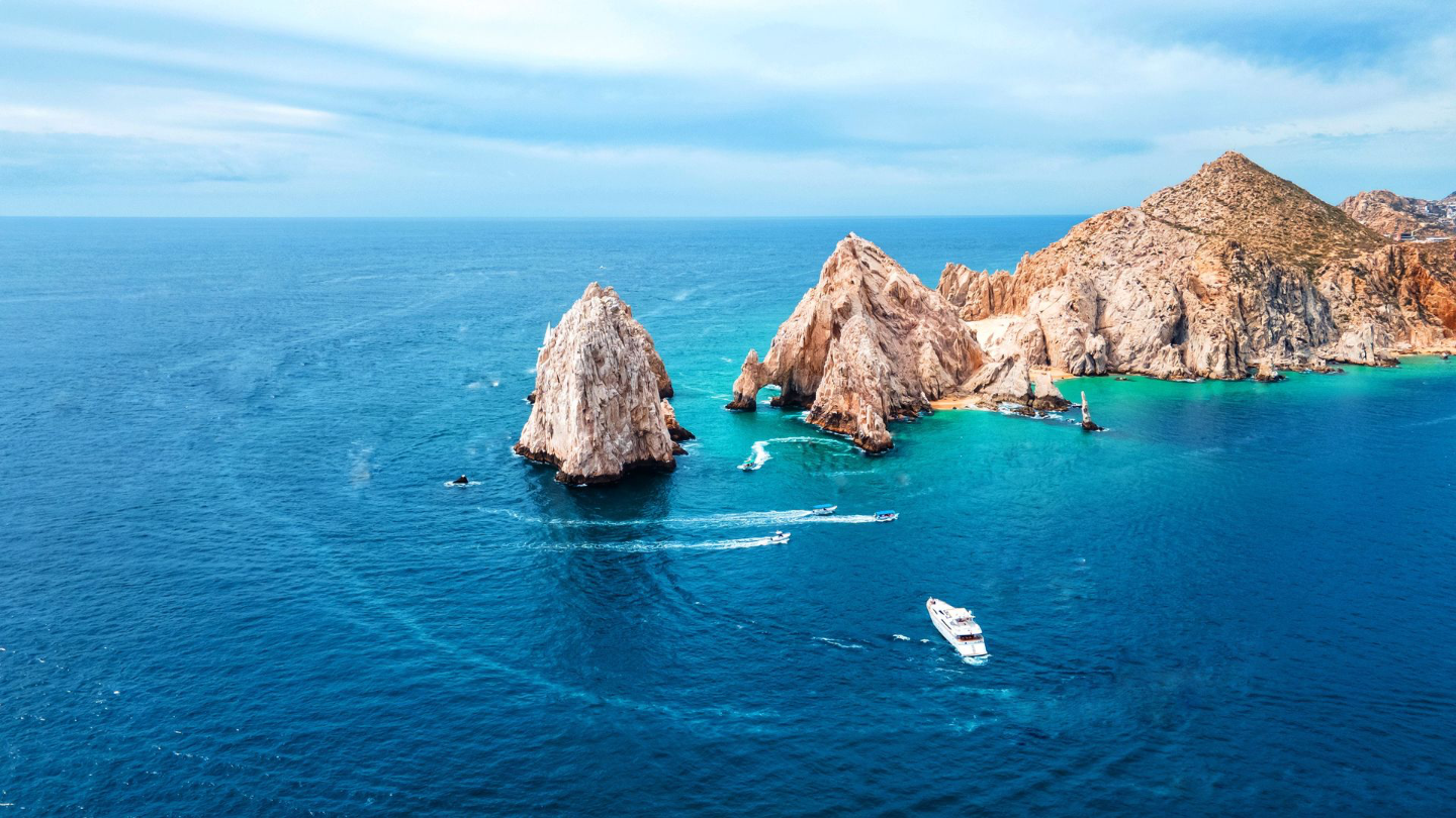 Superbe photo aérienne de l'Arc de Cabo San Lucas avec un océan bleu vibrant et des bateaux en vue.