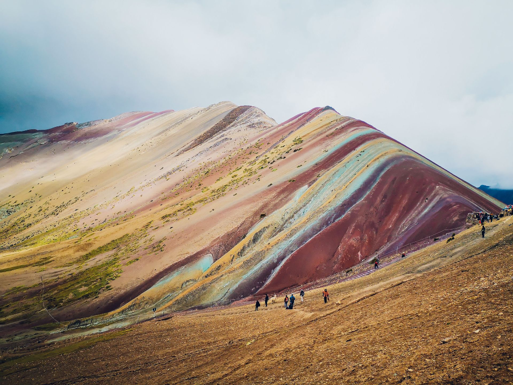 Paysage éclatant de la Montagne Arc-en-ciel avec des randonneurs explorant ses pentes colorées.