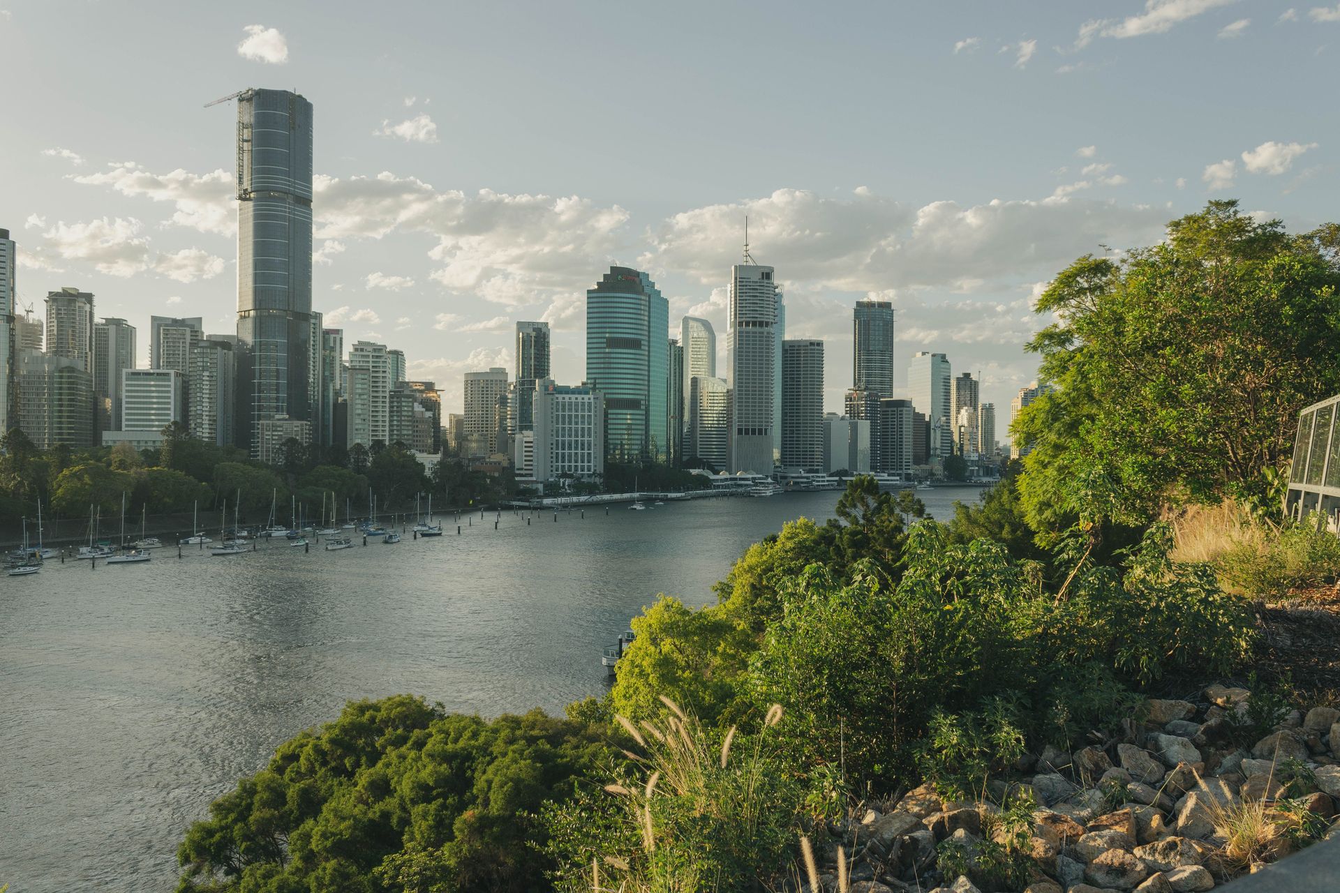 Vue imprenable sur la skyline moderne de Brisbane et la verdure luxuriante au bord de la rivière.