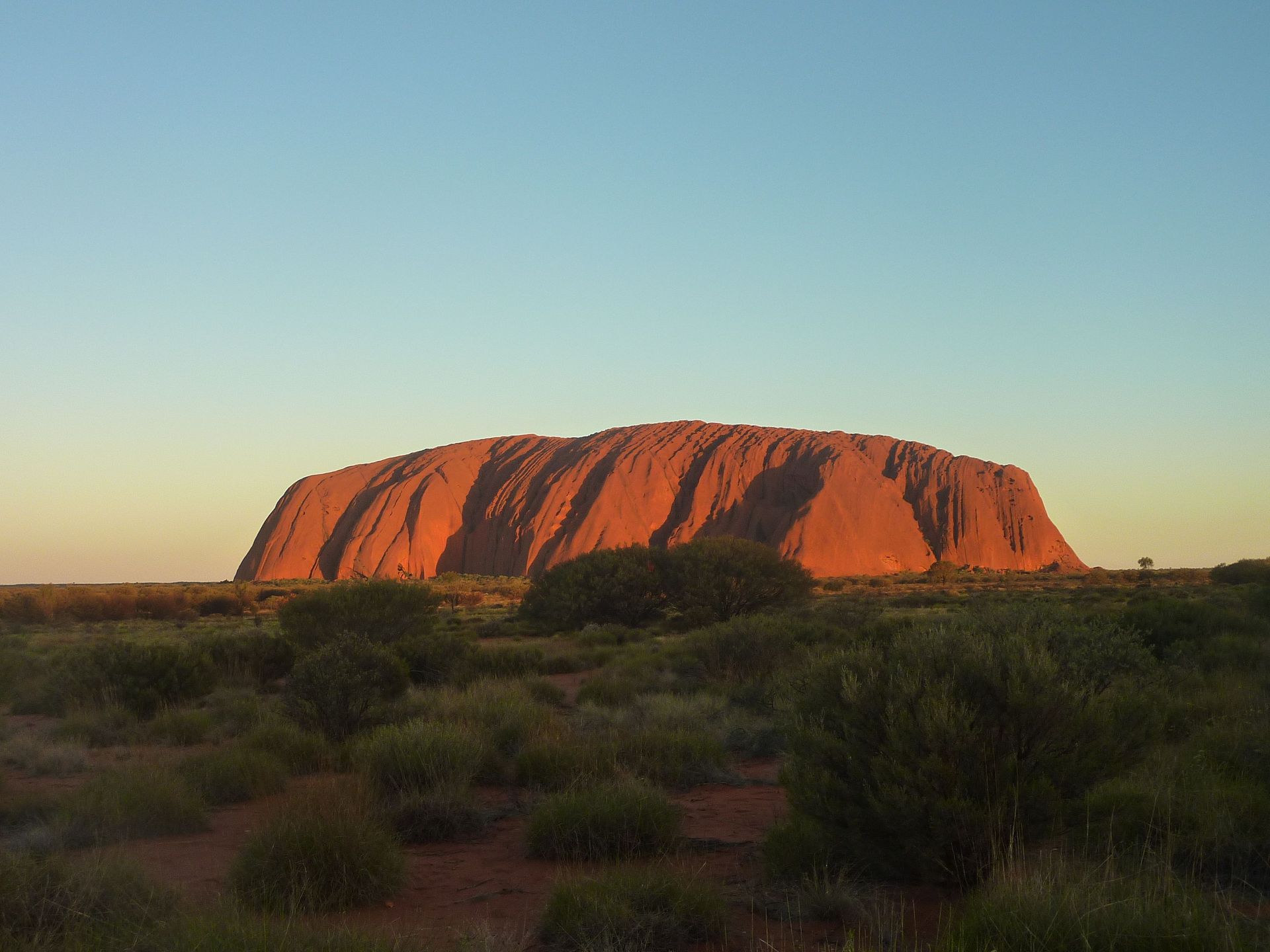 Capturez la majestueuse formation rocheuse d'Uluru rayonnant sous le coucher de soleil. Une merveille naturelle dans l'Outback australien.