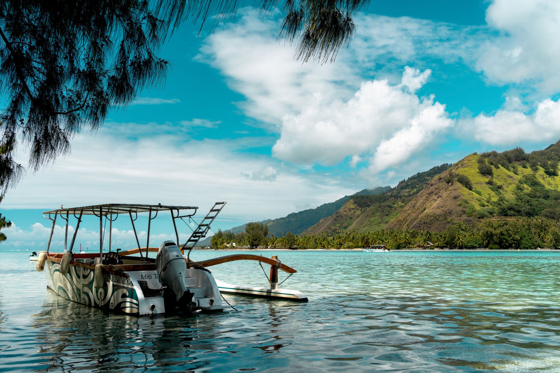Une scène pittoresque d'un bateau reposant dans les eaux calmes de Moorea, Polynésie française, sous un ciel bleu clair.