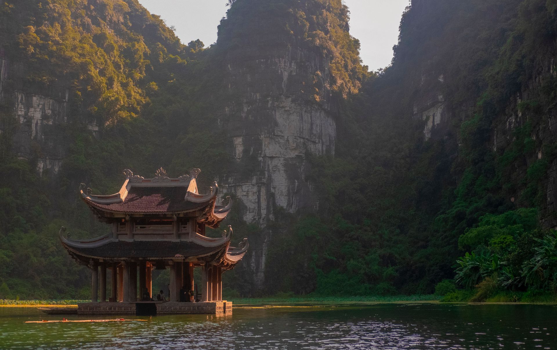 Une pagode tranquille sur un lac entouré de montagnes luxuriantes à Ninh Bình, Vietnam.