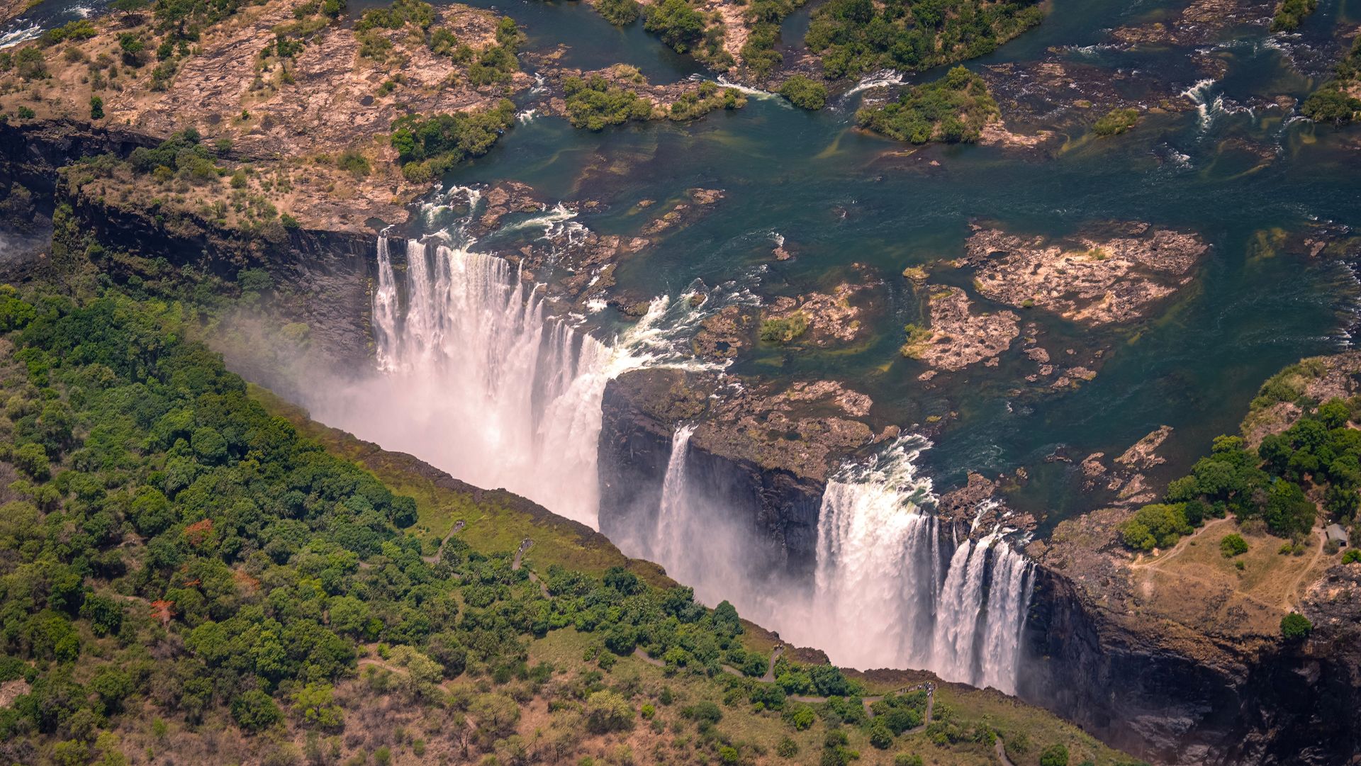 Vue aérienne à couper le souffle des chutes Victoria entourées de verdure luxuriante lors d'une journée d'été.