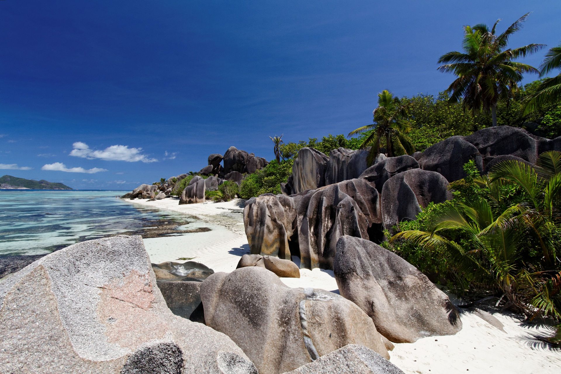 Vue à couper le souffle des formations rocheuses en granit de La Digue et de l'eau turquoise sous un ciel bleu clair.
