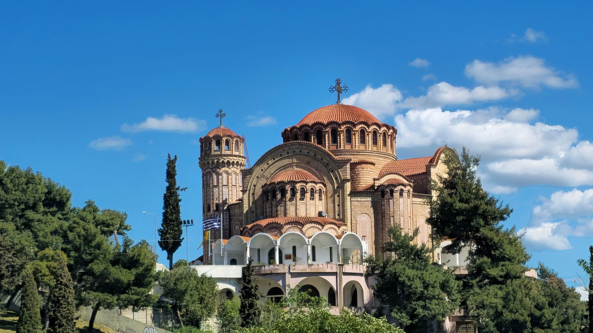 Image captivante de l'Église Saint-Paul à Thessalonique, sous un ciel bleu éclatant avec une végétation luxuriante.