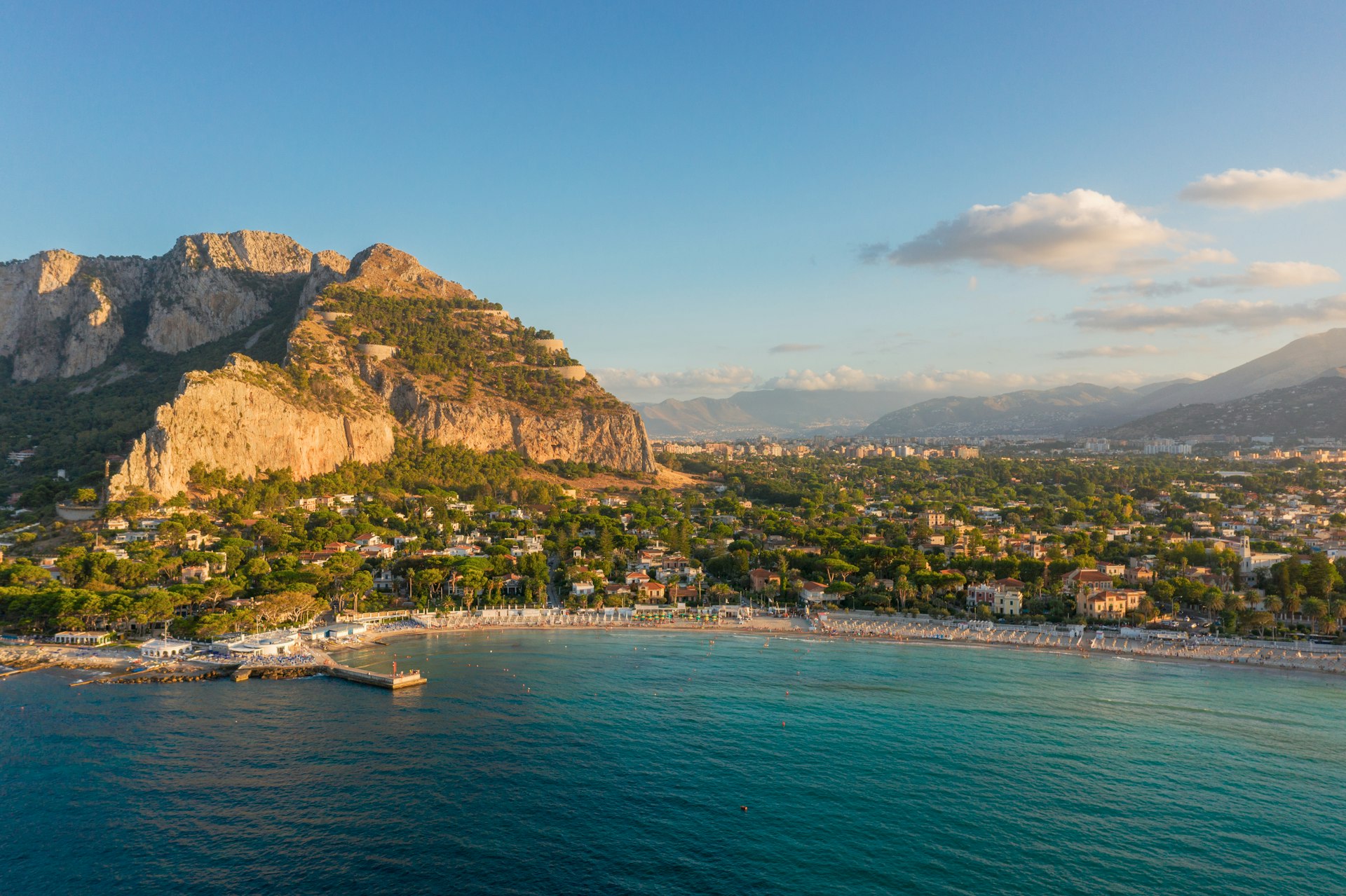 Un bateau blanc sur la mer, près des montagnes de Sicile, en journée.