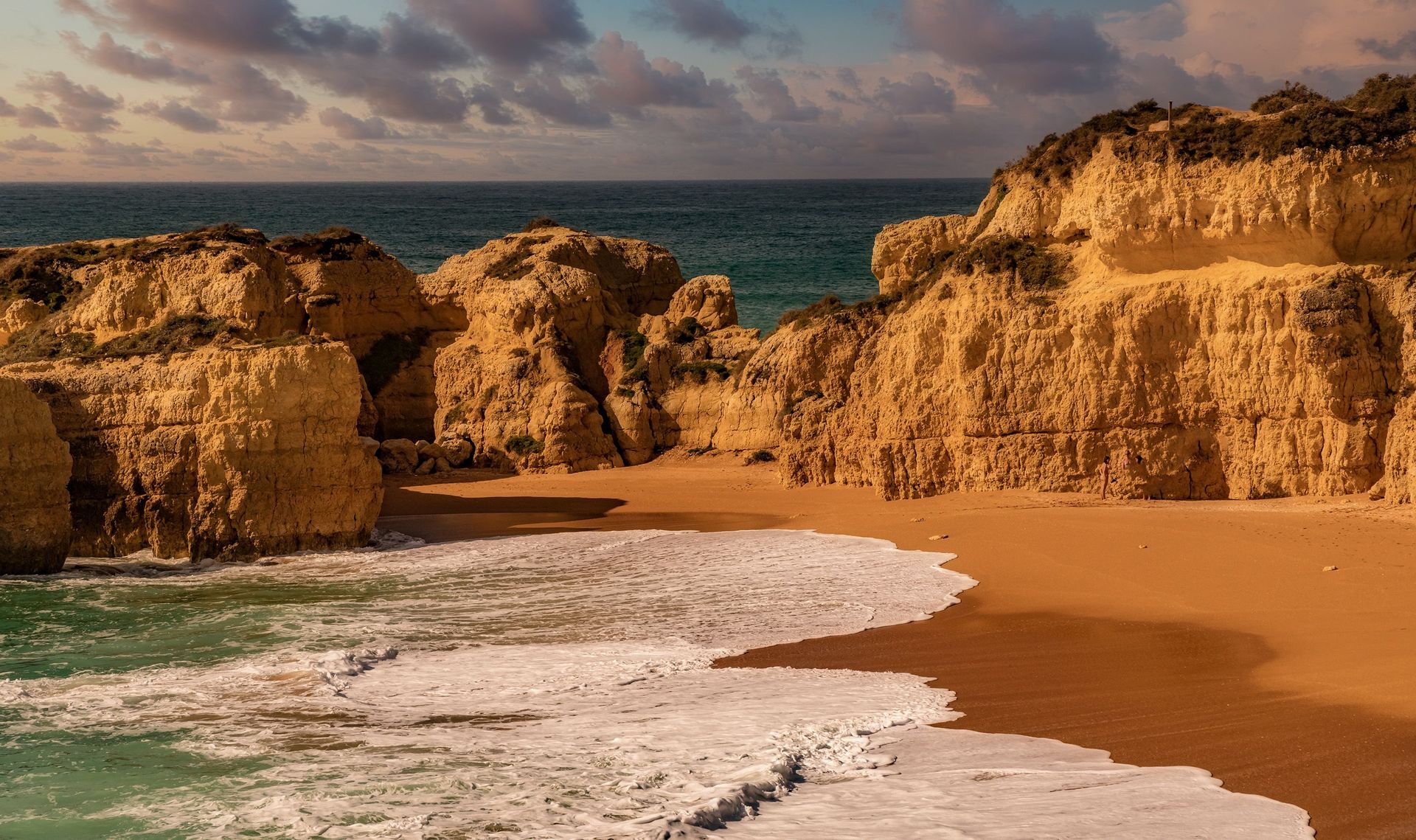 Découvrez la beauté des falaises dorées rencontrant les vagues océaniques sereines au coucher du soleil. Une parfaite tranquillité côtière.