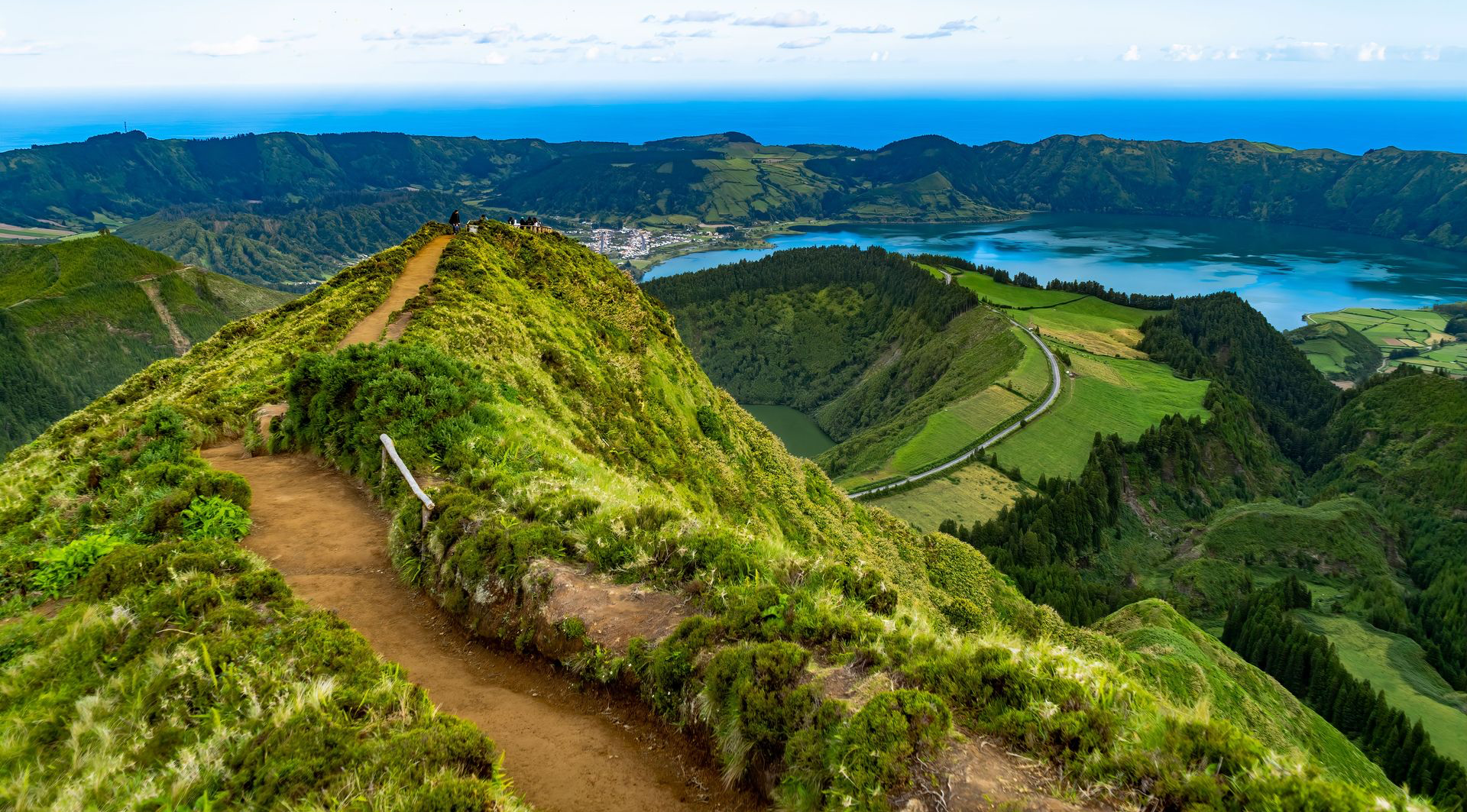 Vue à couper le souffle des collines vertes et de la lagune bleue des Açores sous des nuages dramatiques.