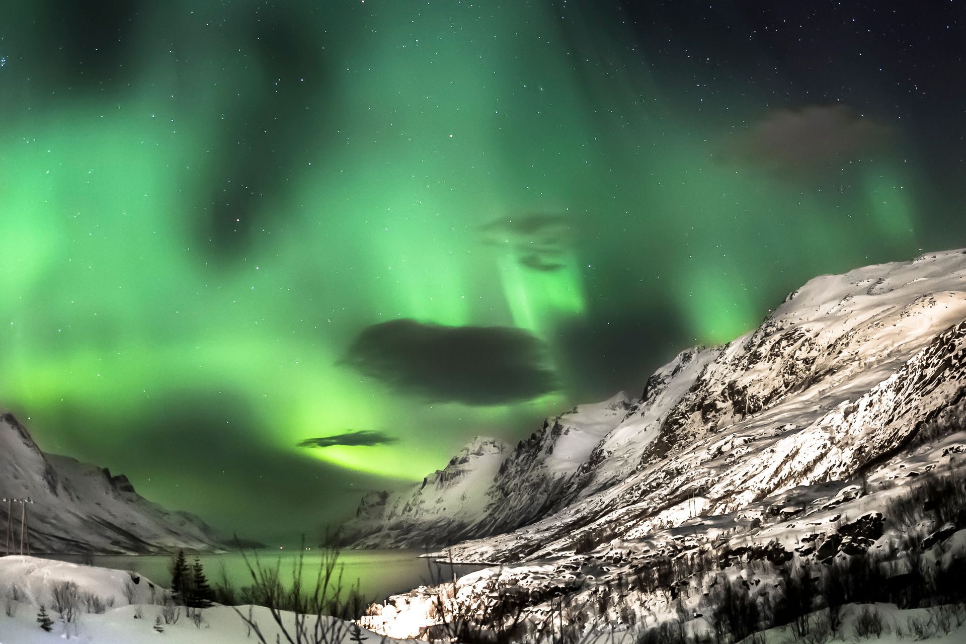Éblouissante aurore boréale sur des montagnes enneigées près d'Oslo, capturant la magie hivernale de la nature.