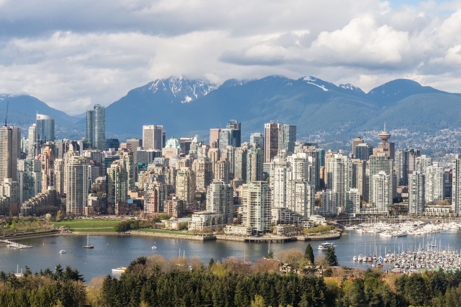 Vue imprenable sur le skyline de Vancouver avec des montagnes et une marina en arrière-plan.