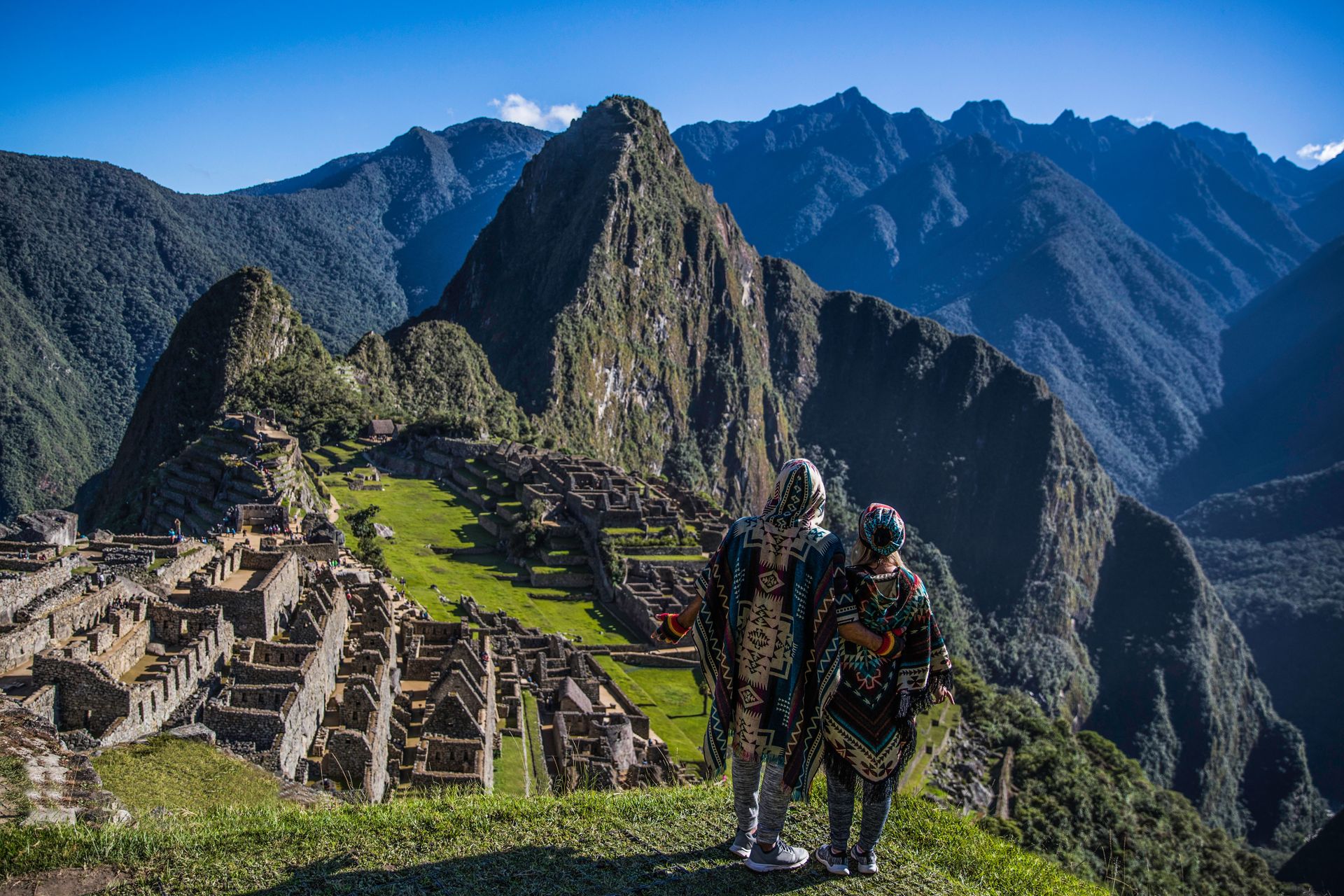 Un couple en ponchos traditionnels admire la vue à couper le souffle du Machu Picchu au Pérou.
