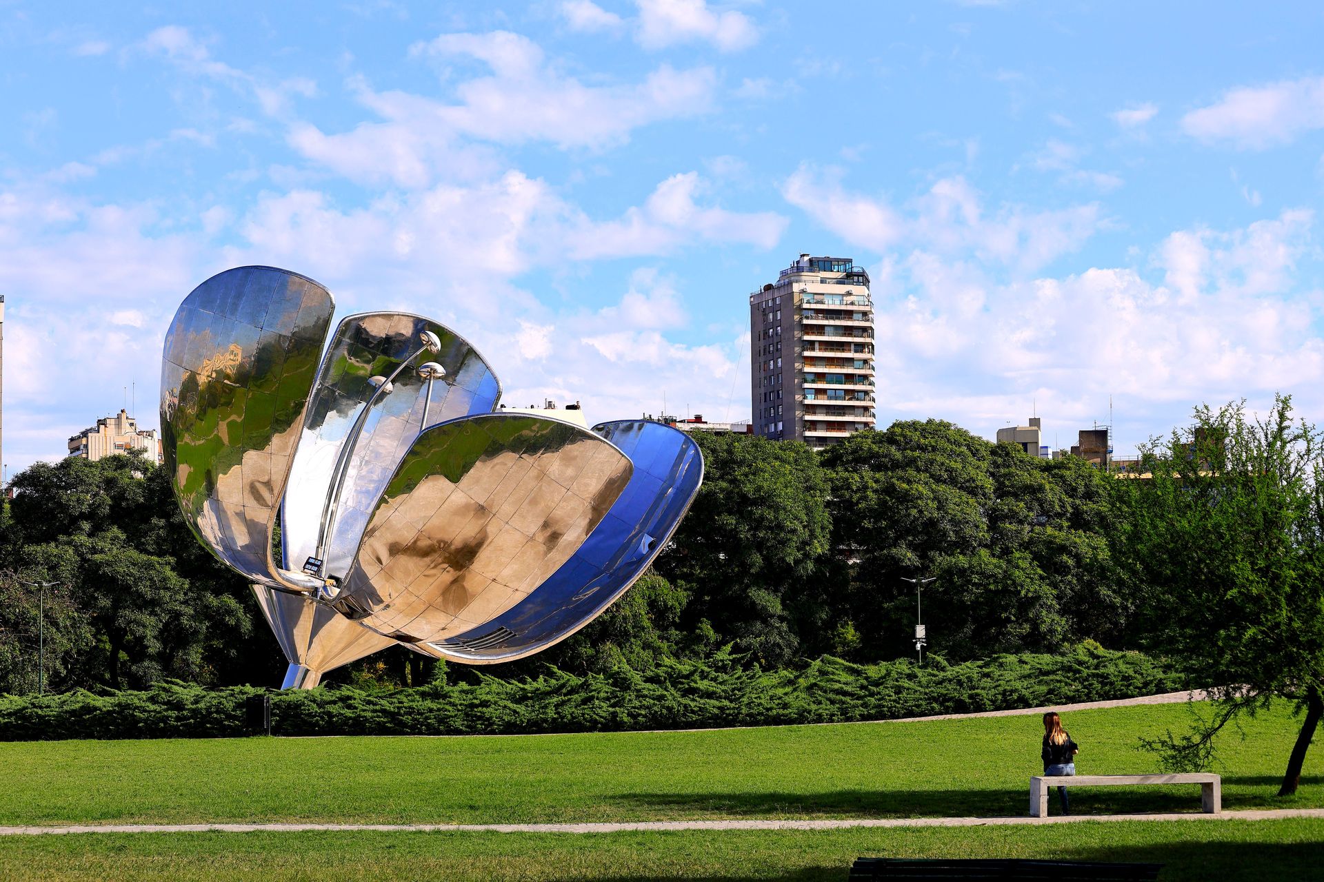 Sculpture Floralis Generica dans un parc de Buenos Aires, avec des bâtiments en arrière-plan.