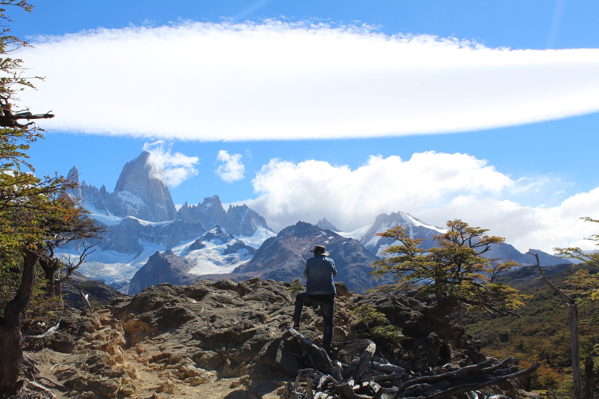 Un randonneur solitaire admire la vue imprenable sur le mont Fitz Roy en Patagonie, sous un ciel d'un bleu limpide.