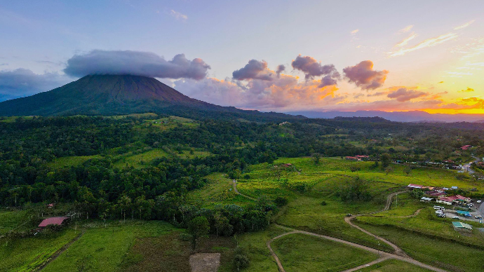 Vue aérienne époustouflante du Volcan Arenal au coucher de soleil dans la province d'Alajuela, mettant en valeur des paysages luxuriants.