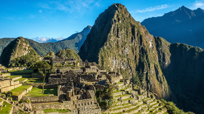 le Machu Picchu en pleine journée sous un grand soleil. en arrière plan, plusieurs montagnes
