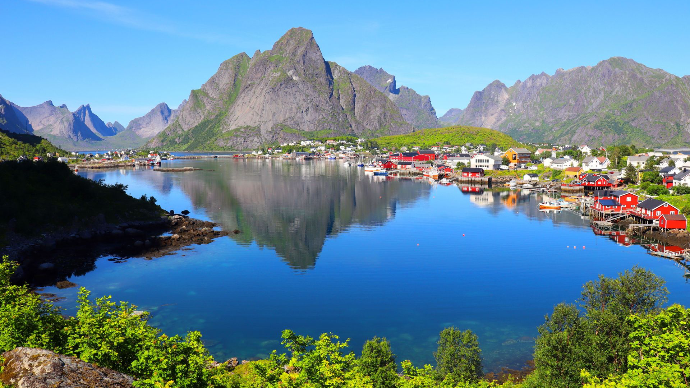 Vue imprenable sur un fjord norvégien avec des maisons colorées et des montagnes sous un ciel d'été clair.